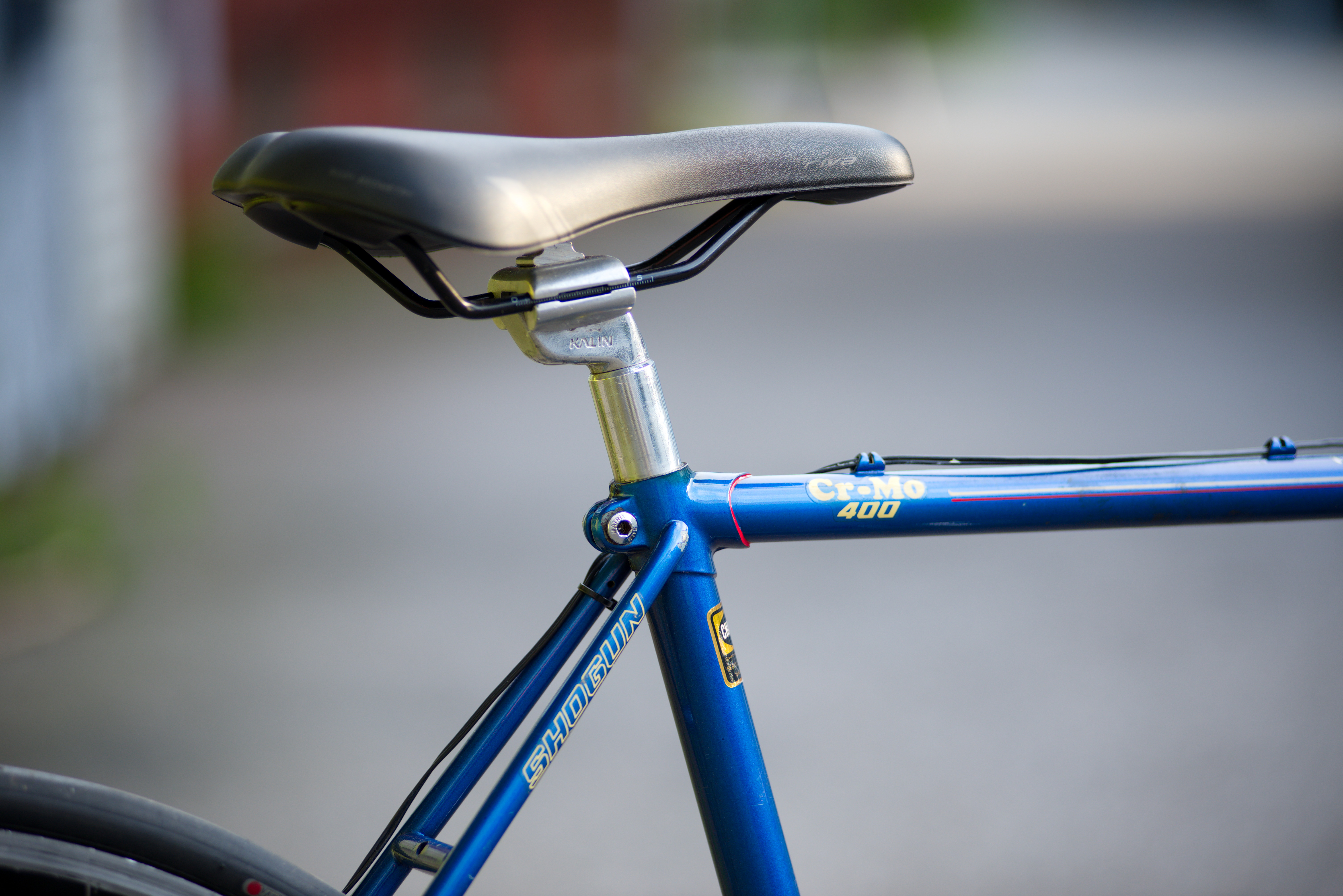 A bicycle saddle, metal seatpost and its clamping point in the frame.