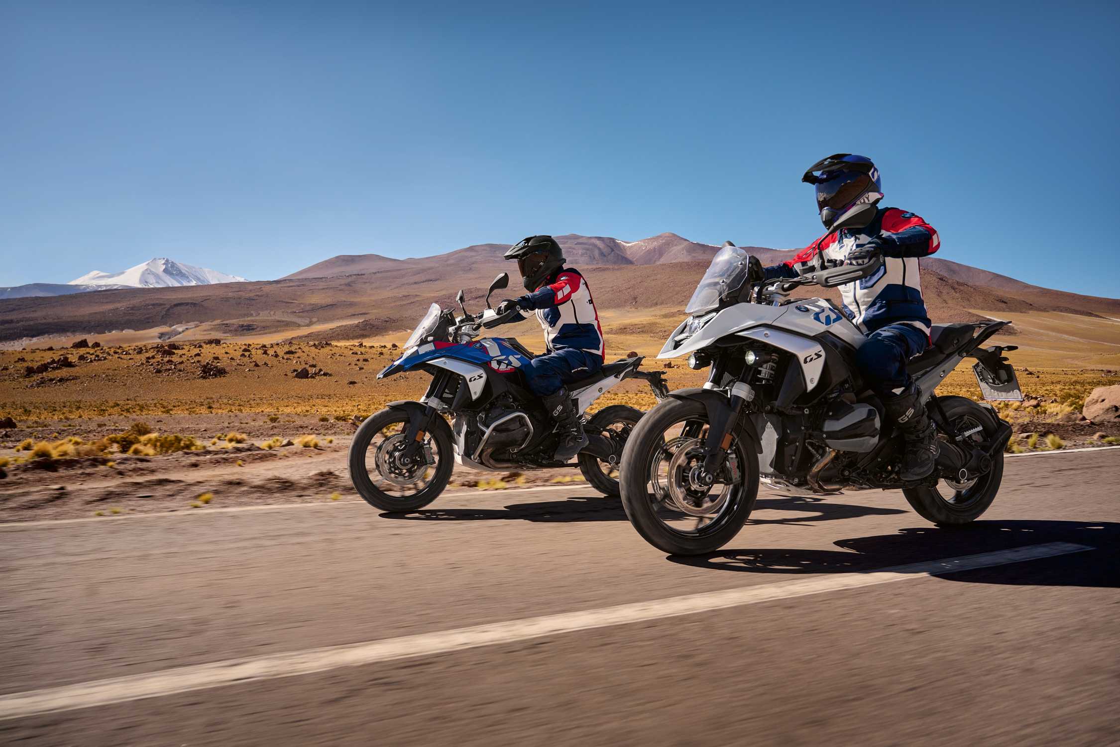 Divi BMW R 1300 GS motocikli uz ceļa kalnu ainavā.