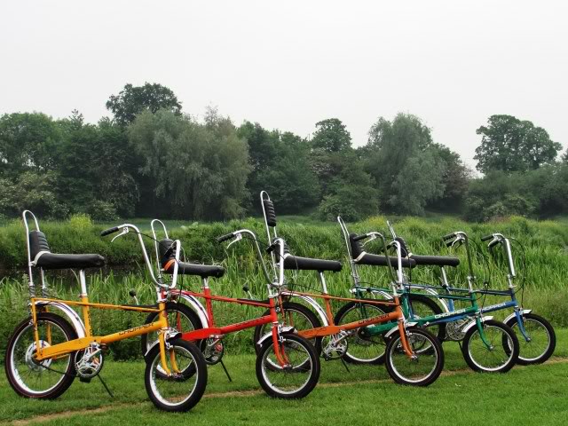 Dažādu krāsu Raleigh Chopper Mk1 velosipēdi rindā zālienā.
