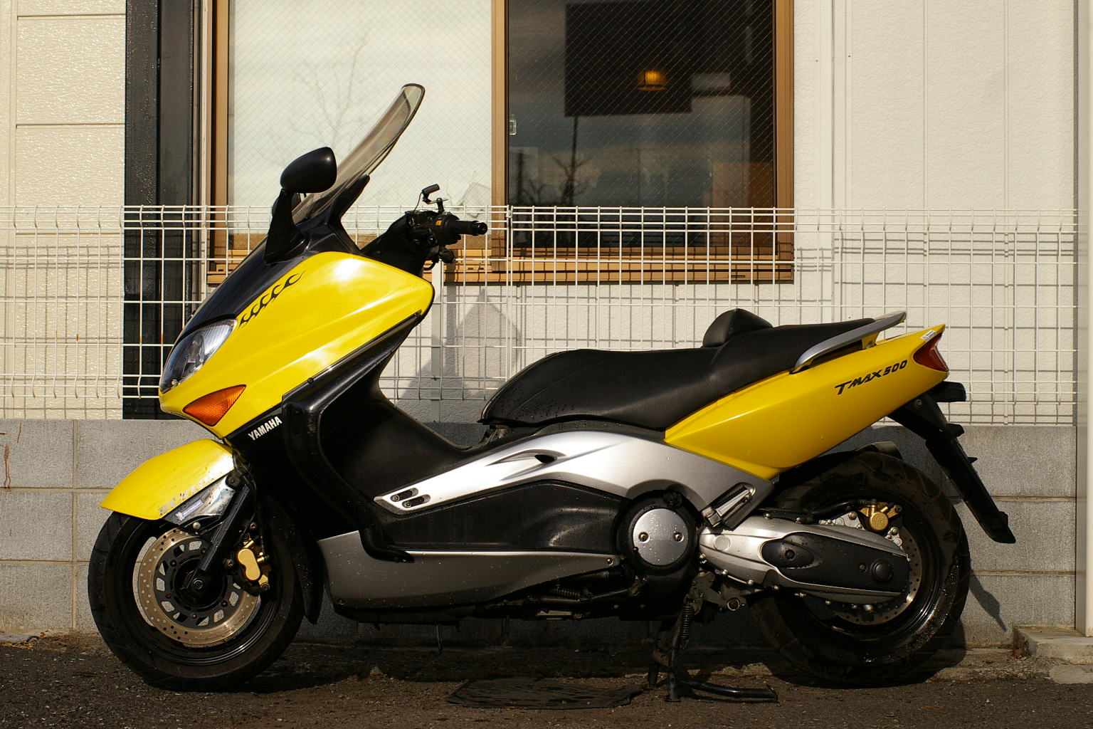 Жёлтый Yamaha TMAX 500 раннего поколения, вид сбоку.